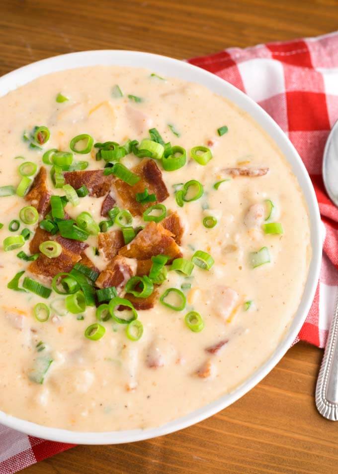 Loaded Potato Soup in a white bowl on a red gingham napkin