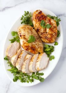 Air Fryer Chicken Breasts on white plate garnished with parsley