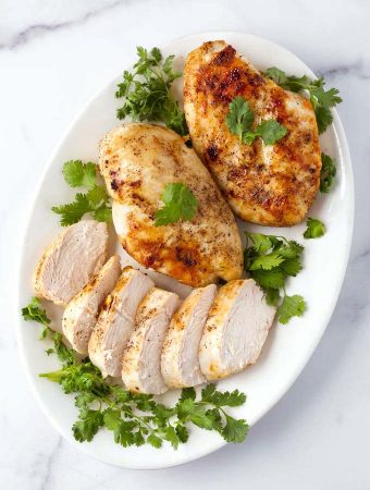 Air Fryer Chicken Breasts on white plate garnished with parsley