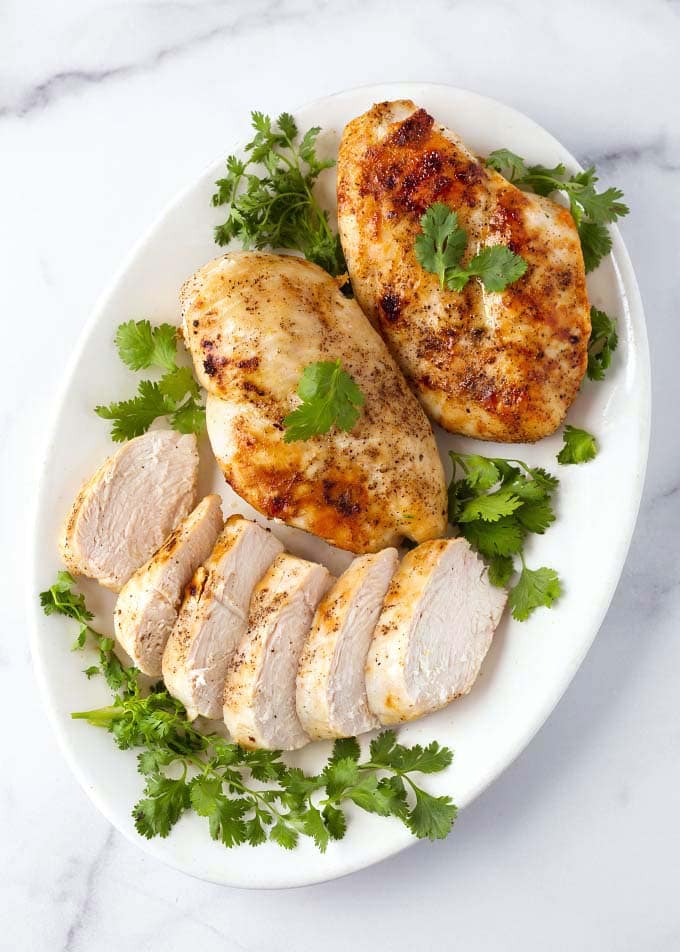 Sliced Air Fryer Chicken Breasts on white plate garnished with parsley