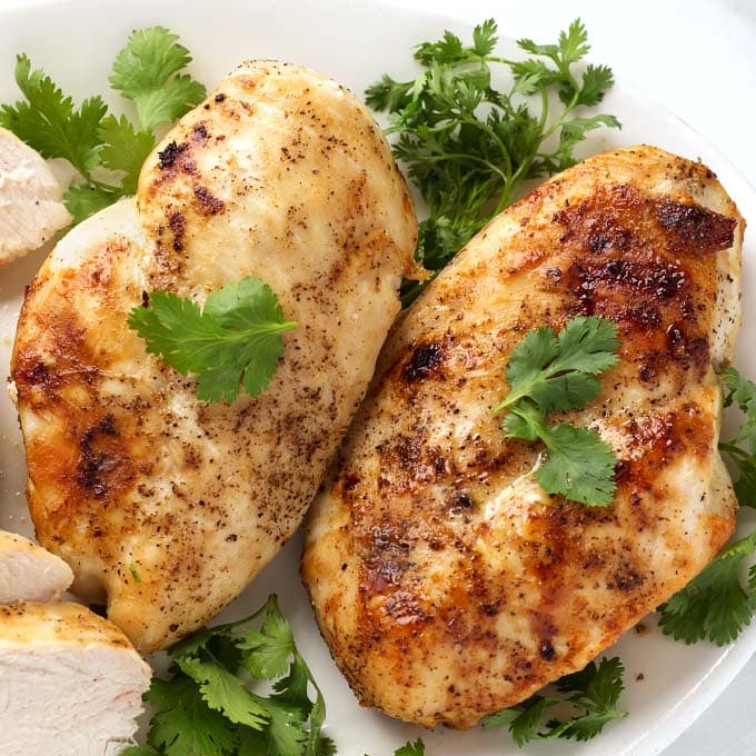 Close up of Air Fryer Chicken Breasts on white plate garnished with parsley