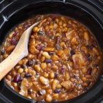 Baked Beans in a slow cooker with wooden mixing spoon