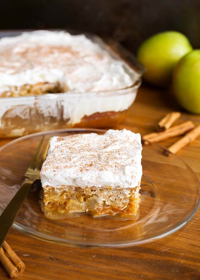 Slice of Caramel Apple Poke Cake on gold plate with fork in front of rest of cake