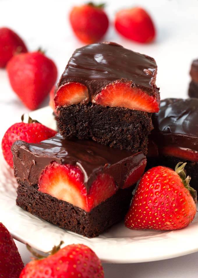 Chocolate Covered Strawberry Brownies on white plate with whole strawberries