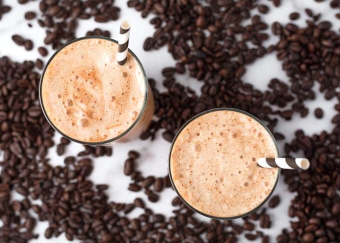 Top view of two Iced Coffee Protein Shakes in glasses surrounded by coffee beans