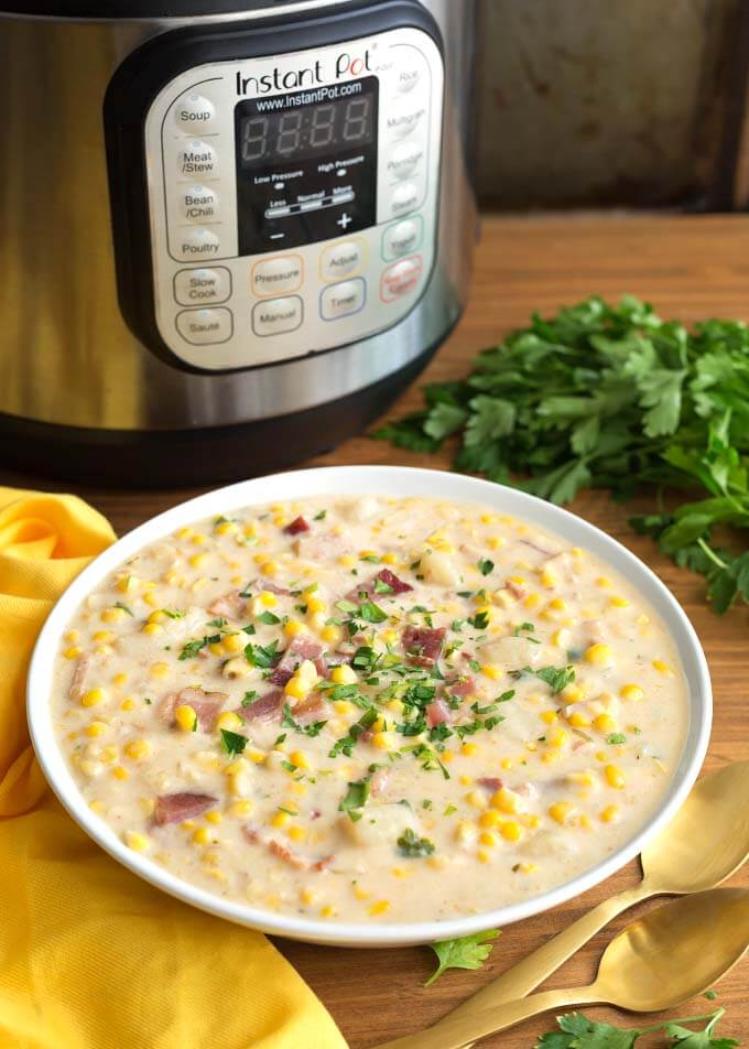 Corn Chowder in white bowl in front of pressure cooker