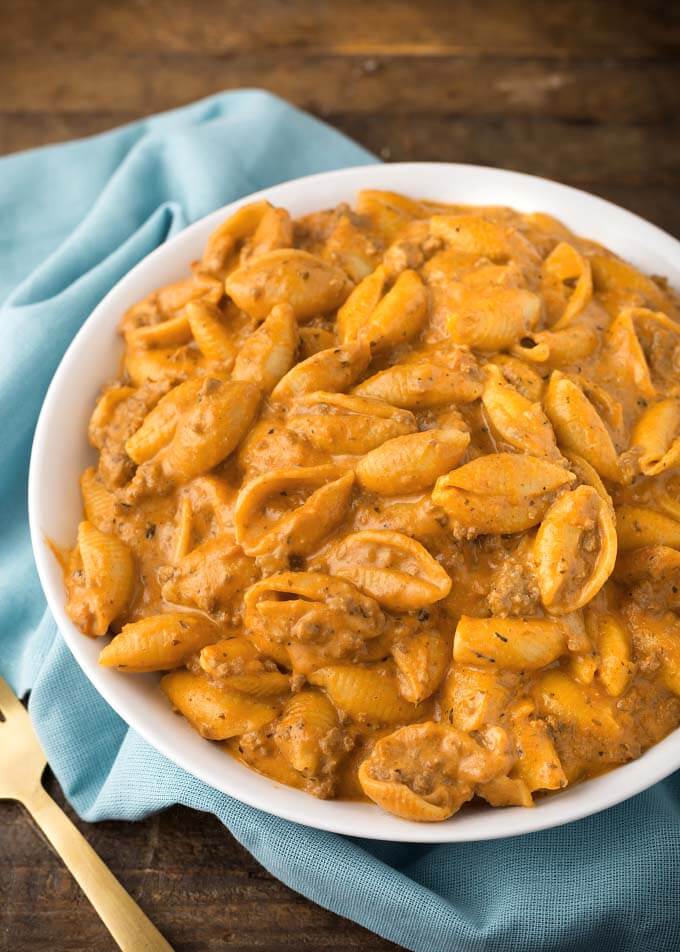 Creamy Beef and Shells in a white bowl next to gold fork