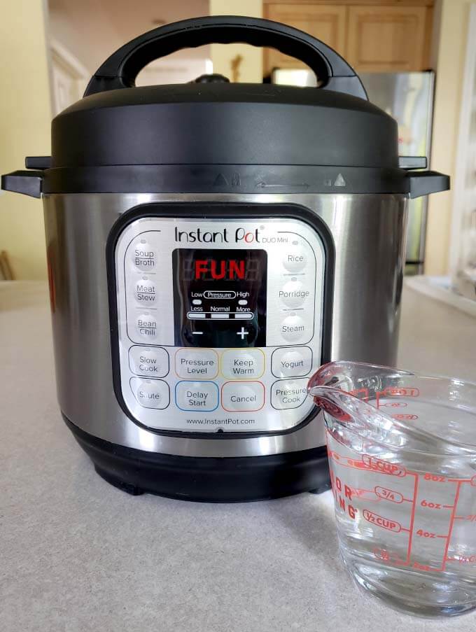 glass measuring cup of water in front of a pressure cooker