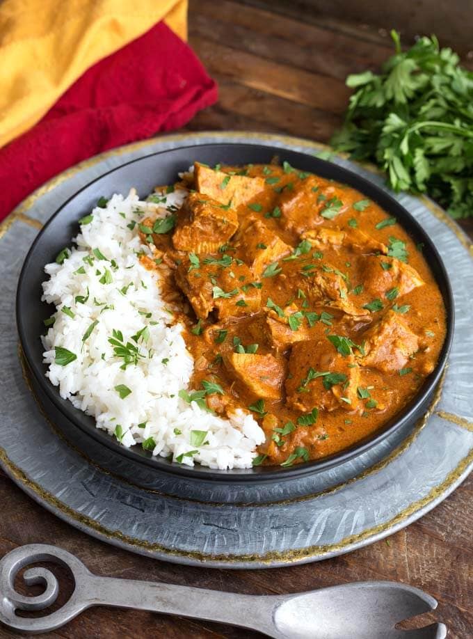 Slow Cooker Indian Butter Chicken with rice on black plate on top of silver platter