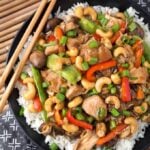 Cashew Chicken over rice on black plate with wooden chopsticks