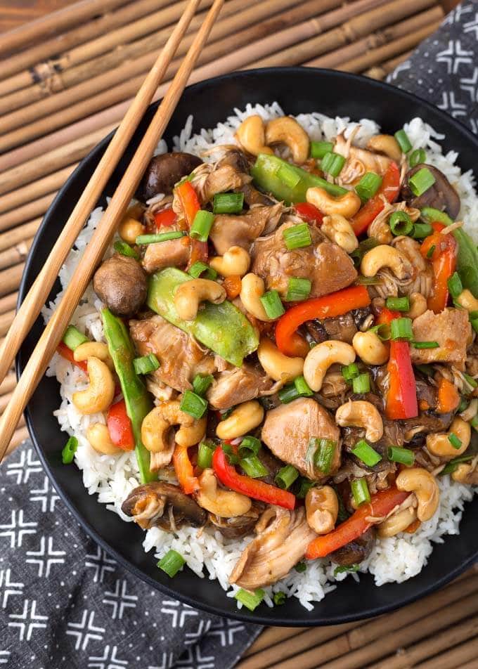 Cashew Chicken over rice on black plate with wooden chopsticks