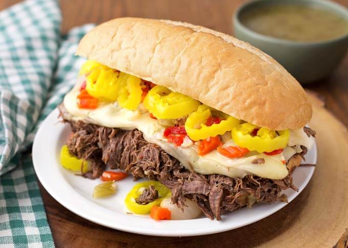 Italian Beef hoagie on white plate on wooden board