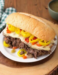 Italian Beef hoagie on white plate on wooden board