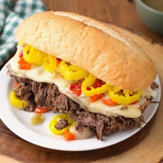 Italian Beef hoagie on white plate on wooden board