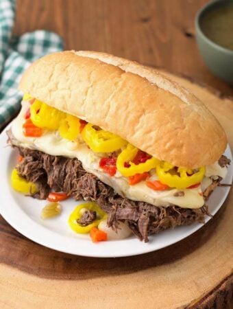 Italian Beef hoagie on white plate on wooden board