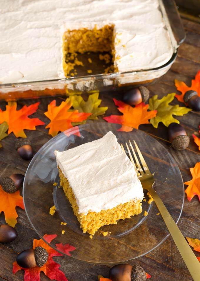 Slice of Pumpkin Cake with Cinnamon Butterscotch Frosting on glass plate in front of rest of cake