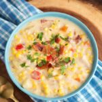 Slow Cooker Corn Chowder in a light blue bowl on blue plaid napkin