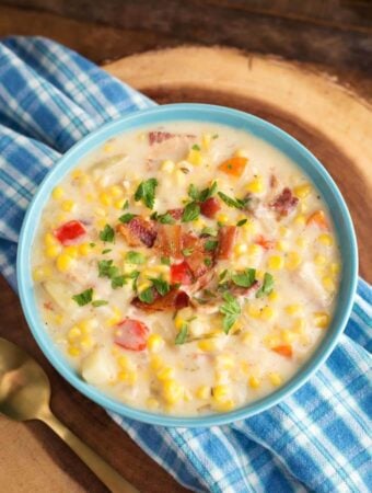 Slow Cooker Corn Chowder in a light blue bowl on blue plaid napkin