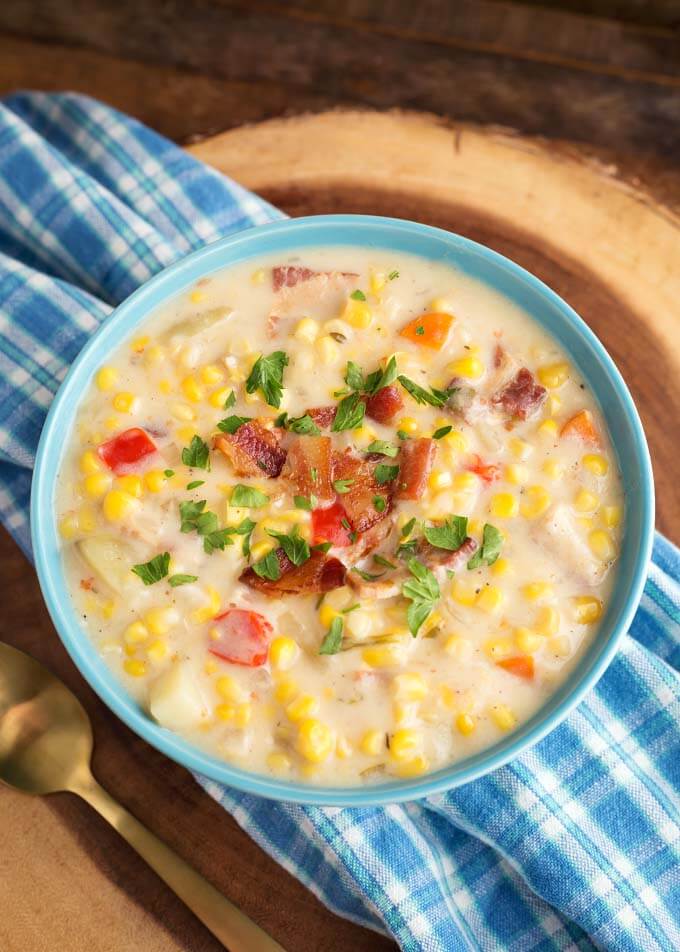 Slow Cooker Corn Chowder in a light blue bowl on blue plaid napkin