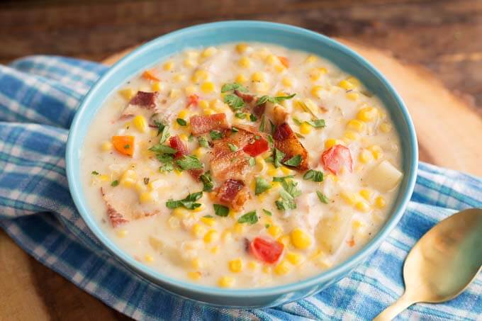 Slow Cooker Corn Chowder in a light blue bowl on blue plaid napkin