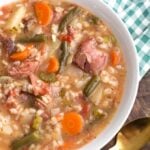 Slow Cooker Ham Vegetable Barley Soup in white bowl on top of green gingham napkin