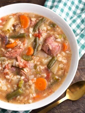 Slow Cooker Ham Vegetable Barley Soup in white bowl on top of green gingham napkin