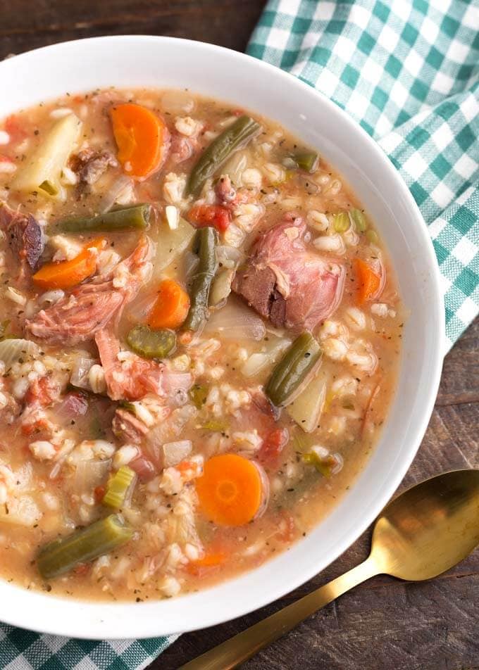 Slow Cooker Ham Vegetable Barley Soup in white bowl on top of green gingham napkin