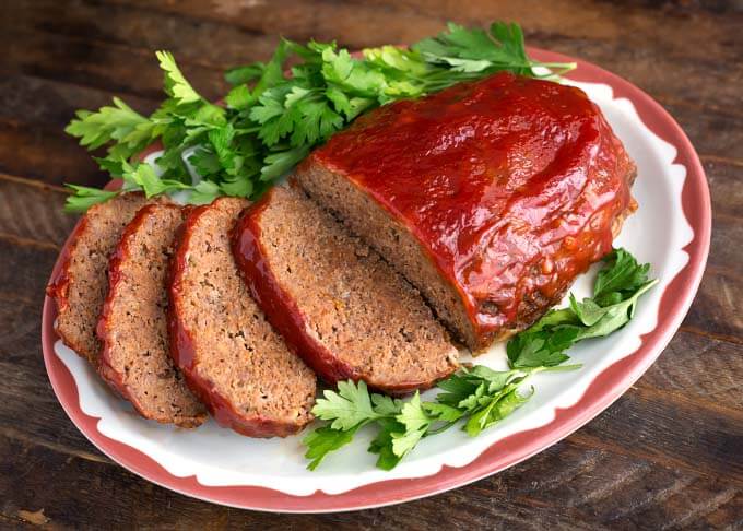 Sliced Meatloaf on white plate garnished with fresh parsley