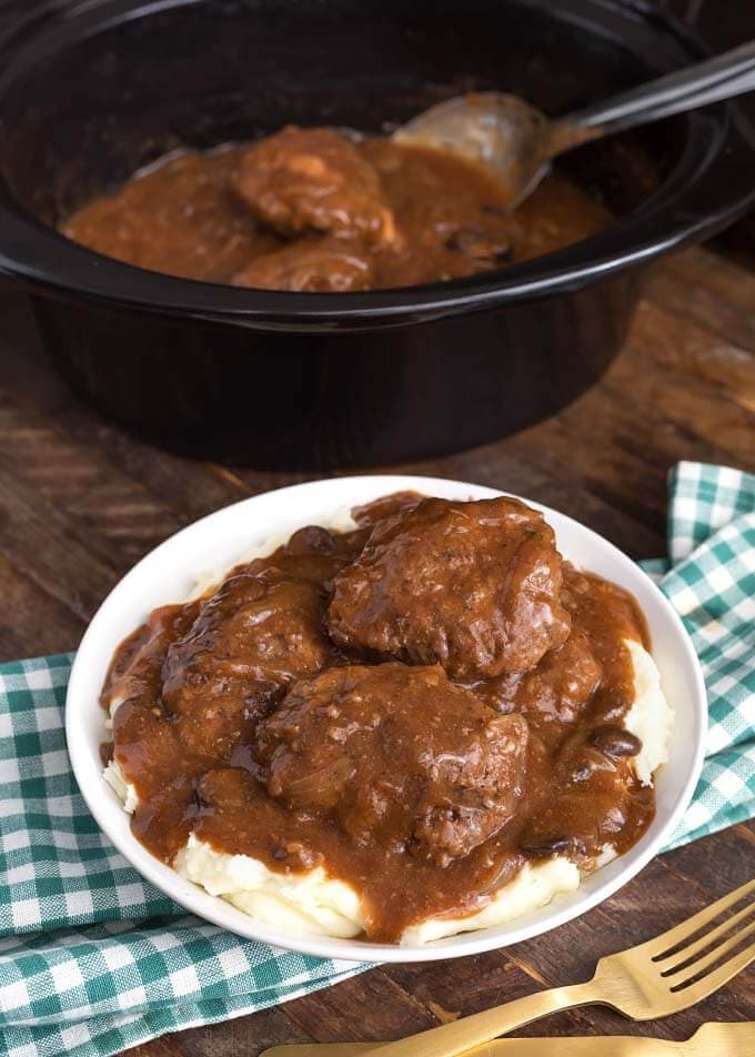 Salisbury Steak on white plate in front of slow cooker