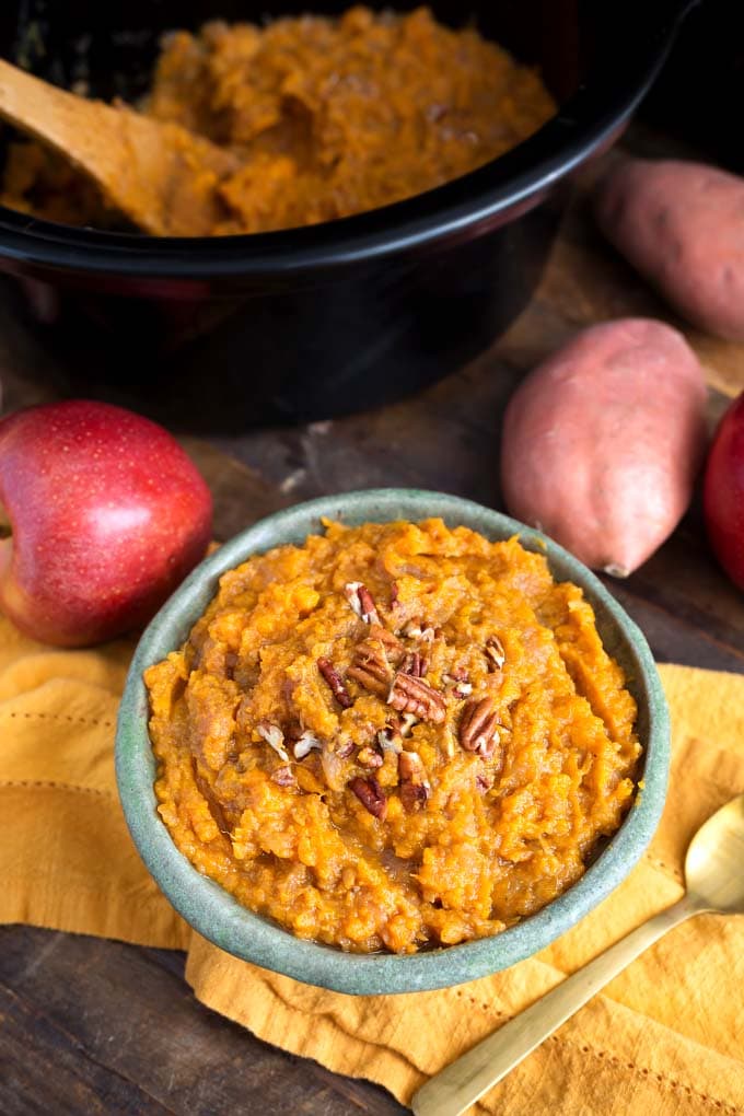 Sweet Potatoes and Apples in light turquoise bowl in front of apples and Slow Cooker