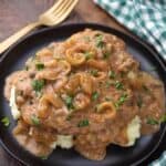 Pressure Cooker Cube Steak with Onion Gravy on black plate
