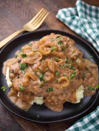 Pressure Cooker Cube Steak with Onion Gravy on black plate