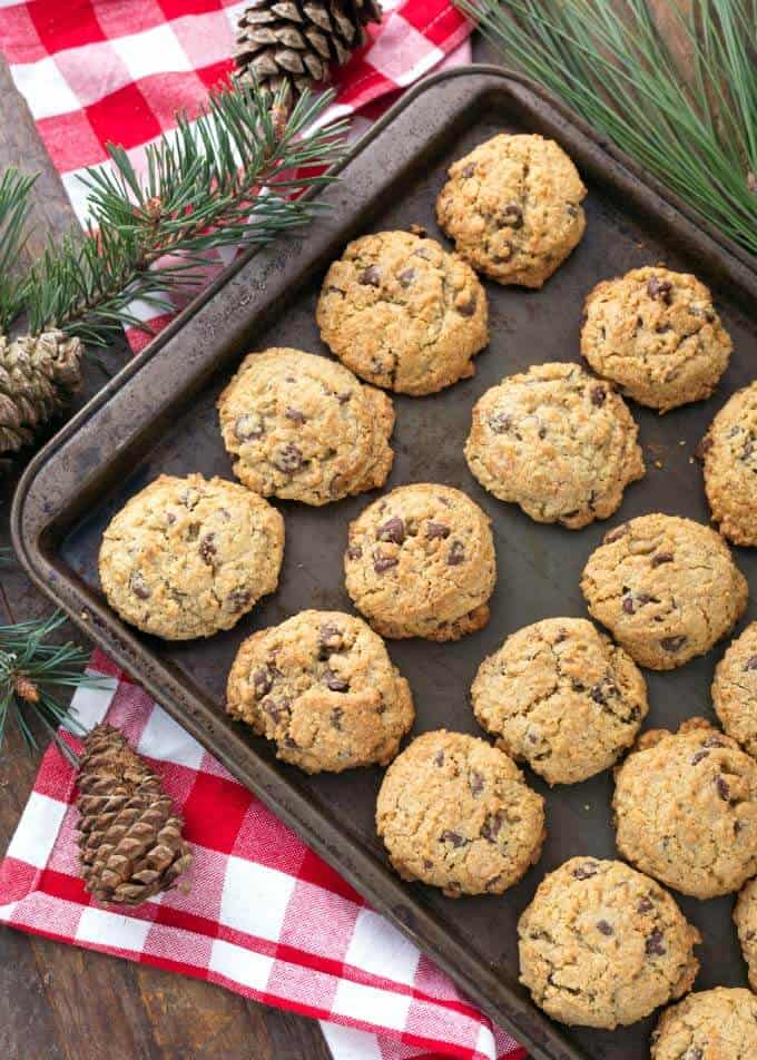 Several Chocolate Chip Oatmeal Cookies on baking sheet on top of red gingham napkin