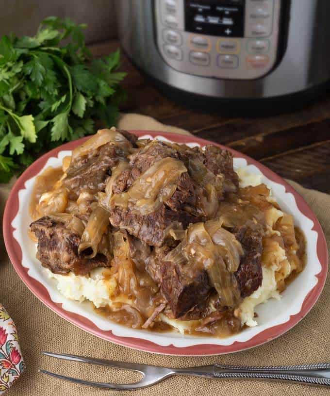 Pressure Cooker French Onion Pot Roast over mashed potatoes on white plate