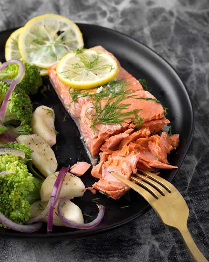 Pressure Cooker Lemon Butter Salmon with vegetables on black plate with gold fork