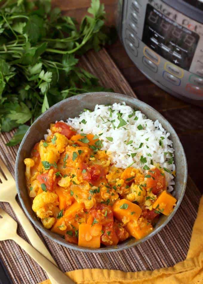 pressure cooker Vegetable Curry with rice in gray bowl next to pressure cooker and two gold forks