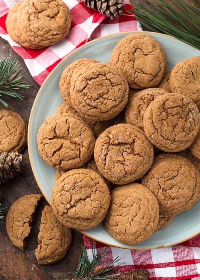 Several Soft Chewy Ginger Cookies on grey plate with red gingham napkin and pine needles in background