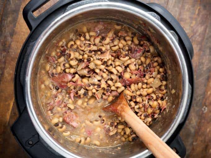 Southern Black Eyed Peas in pressure cooker with wooden mixing spoon