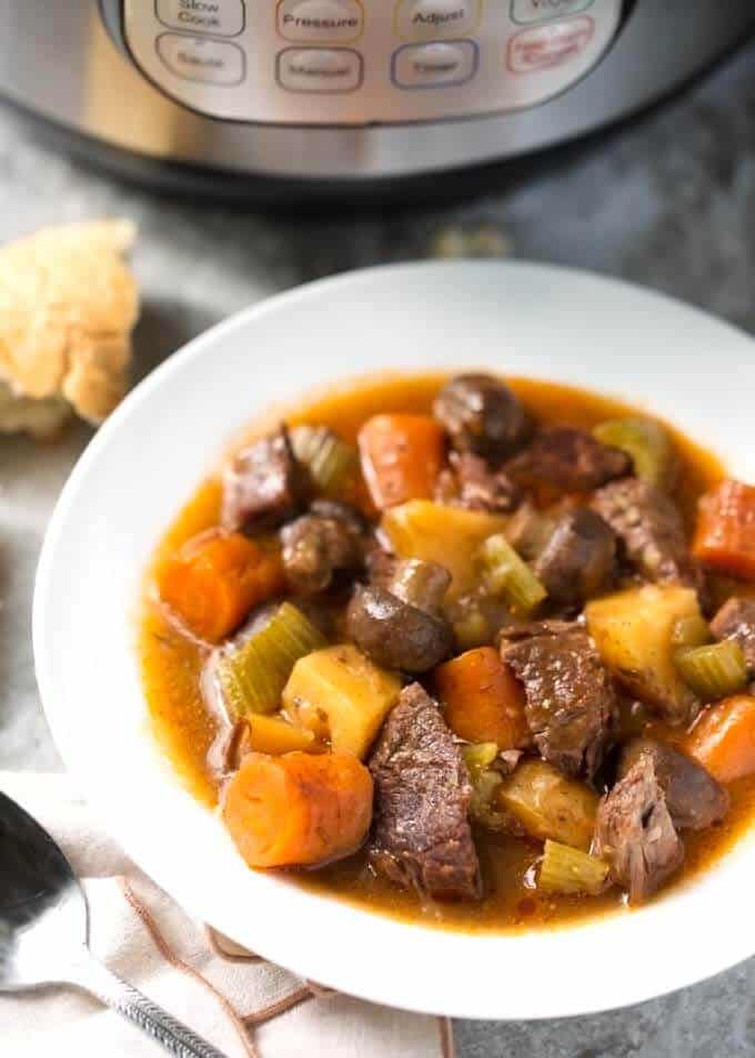 Sandy's Instant Pot Beef Stew in a small white bowl with pressure cooker in the background