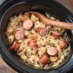 Slow Cooker Sauerkraut and Kielbasa with wooden mixing spoon