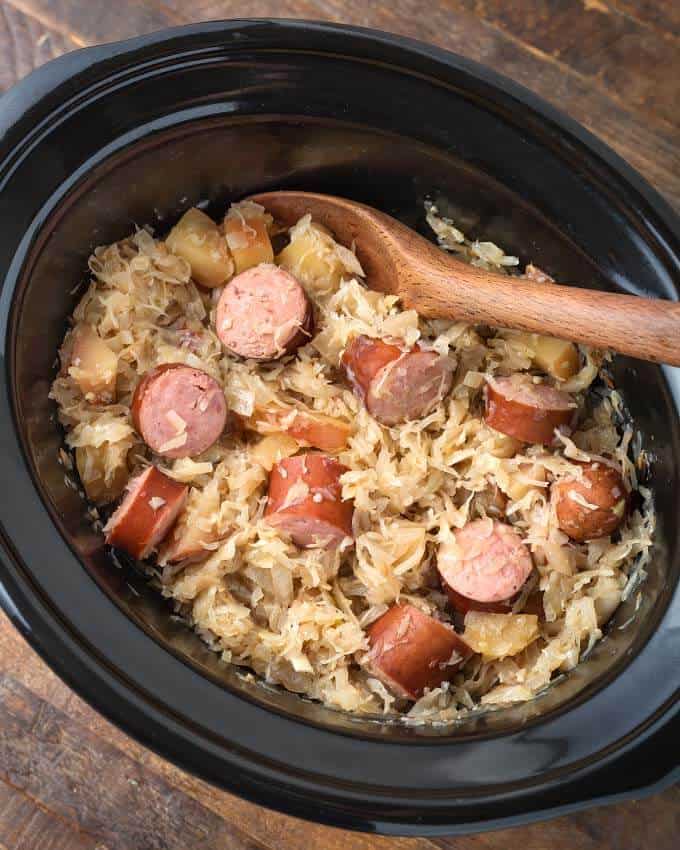 Sauerkraut and Kielbasa in slow cooker with wooden spoon