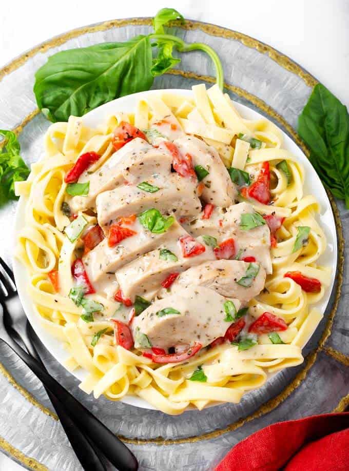 Sliced Pressure Cooker Creamy Italian Chicken Breasts over noodles on white plate