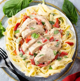 pressure cooker Creamy Italian Chicken Breasts over noodles on a white plate