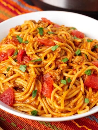 Taco Spaghetti in a white bowl on a red orange striped cloth