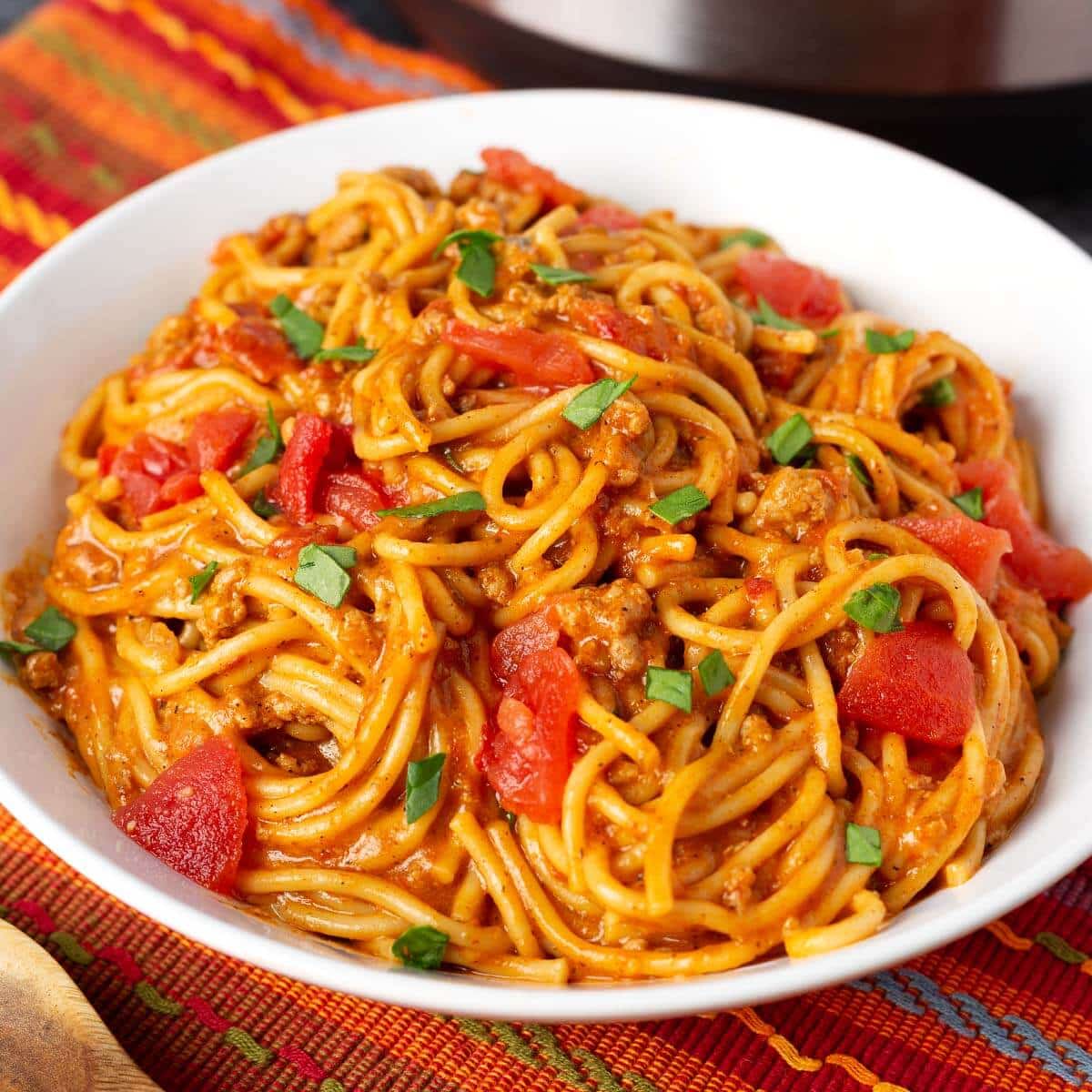 Taco Spaghetti in a white bowl on a red orange striped cloth