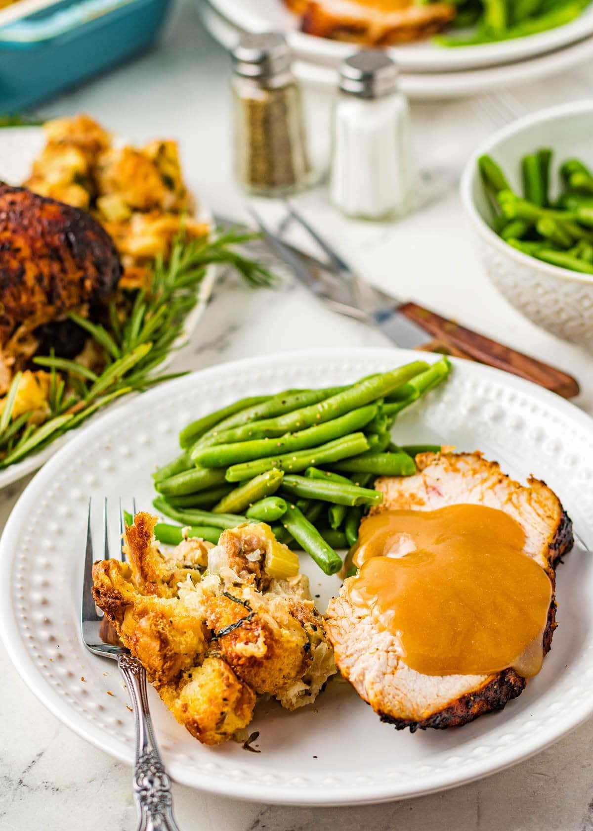 Air Fryer Turkey Breast slice on a white plate with beans and stuffing