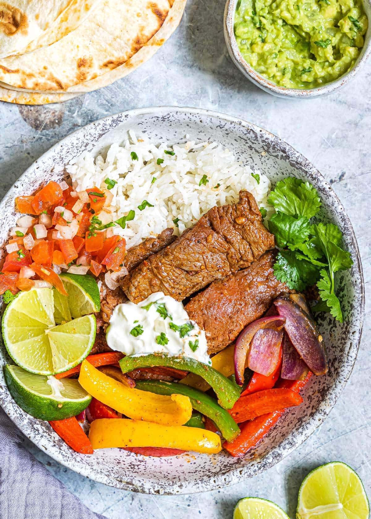 Air Fryer Steak Fajitas on a grey plate with garnishes