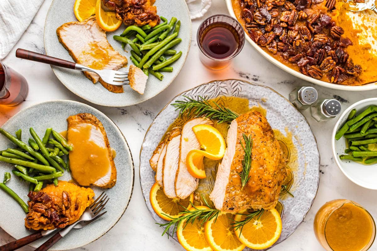 sliced air fryer turkey breast on plate with side dishes and garnishes