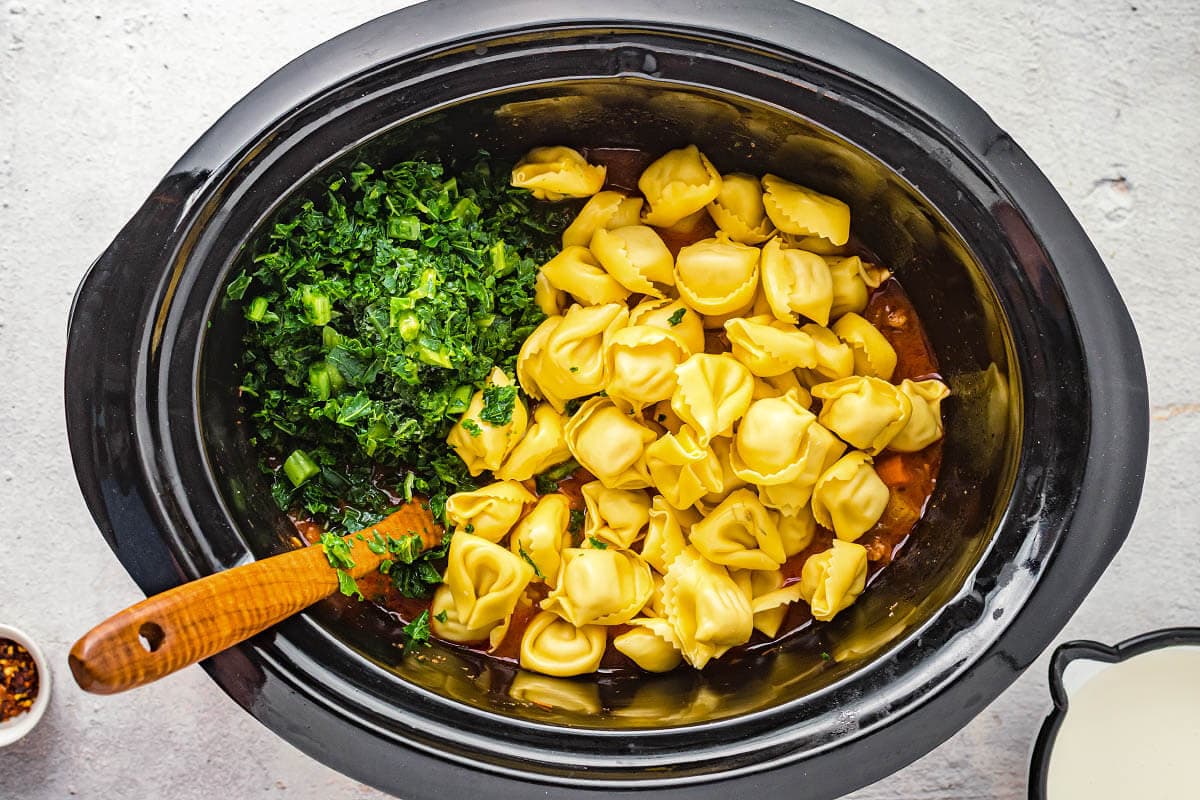 adding tortellini and kale to crock