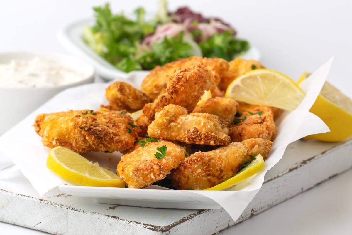 white plate of chicken nuggets and lemon wedge